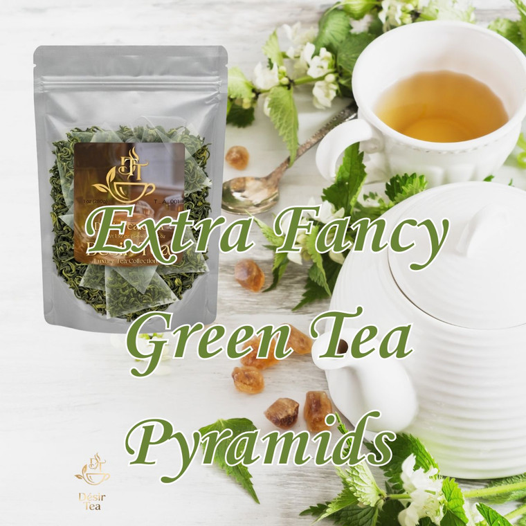 Pyramid tea bags scattered next to a ceramic cup of bright green brew and fresh leaves on a rustic wooden surface.