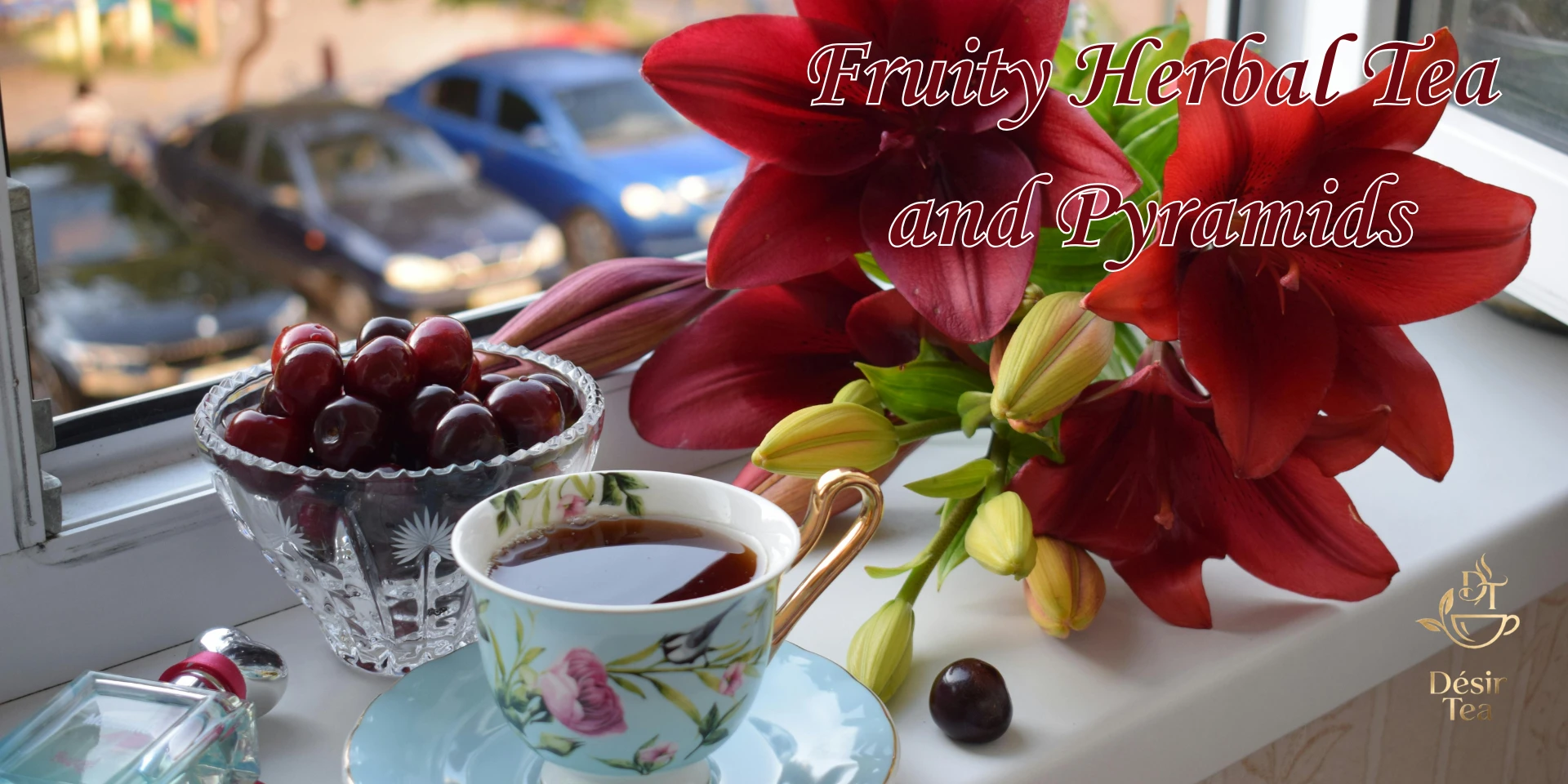 Cup of fruity herbal tea next to fresh cherries and red lilies, with Desir Tea logo.