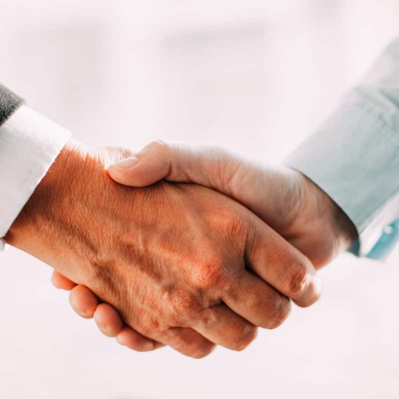 Closeup of two professionals shaking hands after office furniture services agreement.