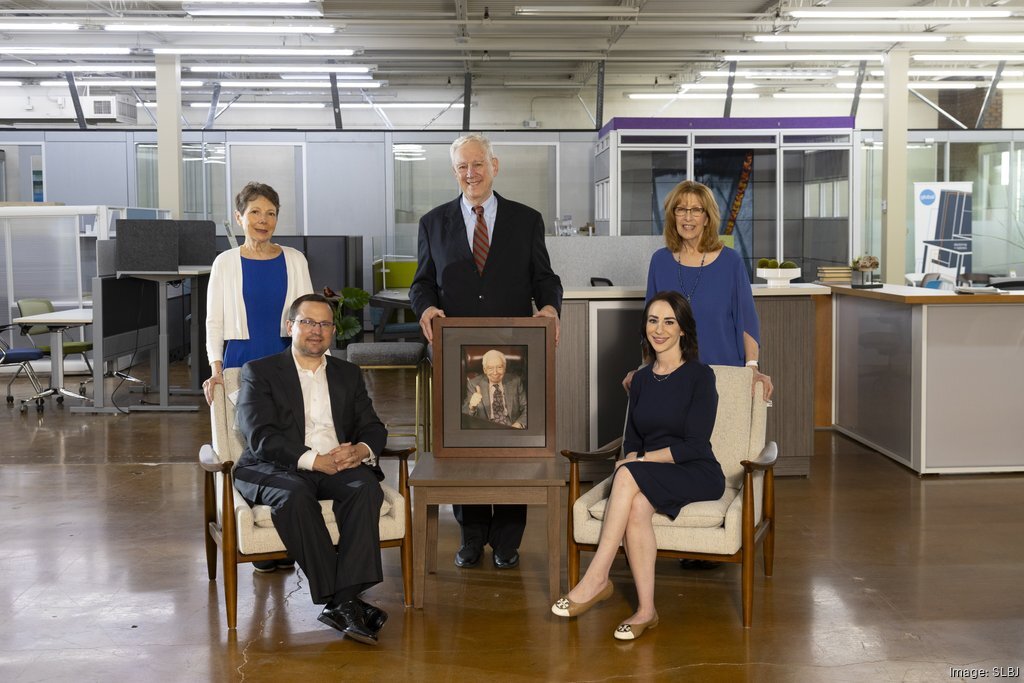 Warehouse of Fixtures leadership team in office furniture showroom with framed portrait of company founder.