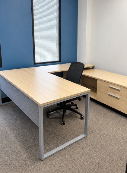 Private office at Gonzalez Companies with light wood furniture and blue accent wall