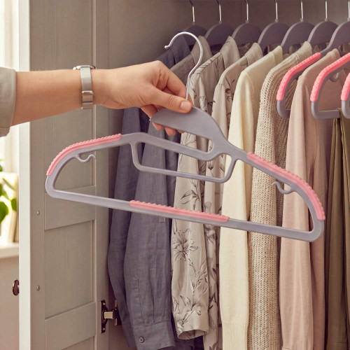 Grey non-slip clothes hangers with pink grips, shown in use in a wardrobe