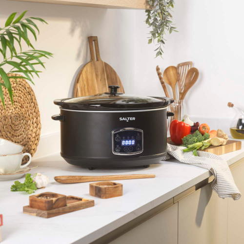 Black slow cooker with spiced winter punch, garnished with orange slices and cranberries