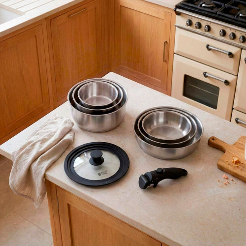 Silver kitchen sink with light beige towel on counter, wooden cabinets and cream stove