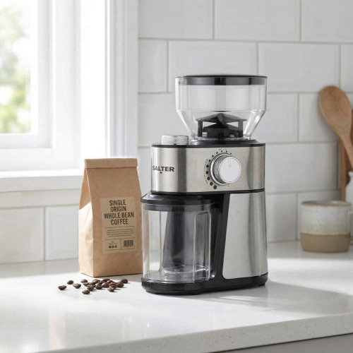Silver electric coffee grinder with bean container on kitchen counter next to coffee beans and a bag.