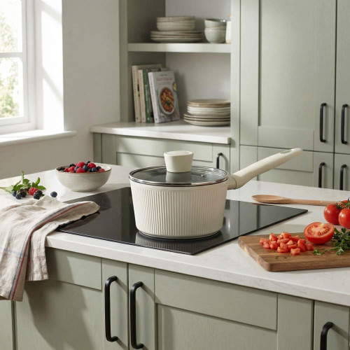 Cream saucepan with lid on induction hob in a modern kitchen