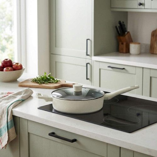 Cream ceramic frying pan with lid on induction hob in modern kitchen