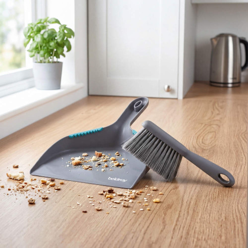 Grey dustpan and brush on kitchen counter with biscuit crumbs