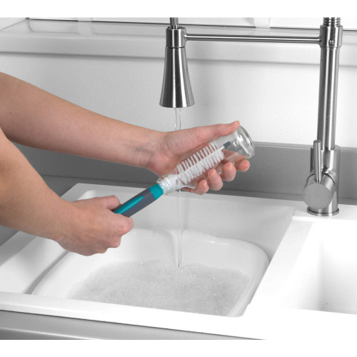 Bottle brush cleaning a clear baby bottle under tap in kitchen sink