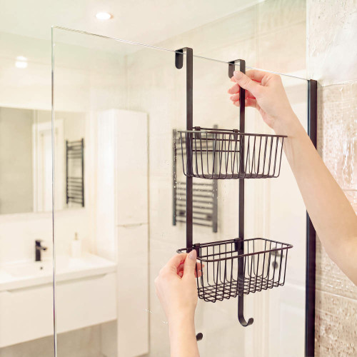 Black hanging shower caddy with two baskets and hooks over glass shower screen