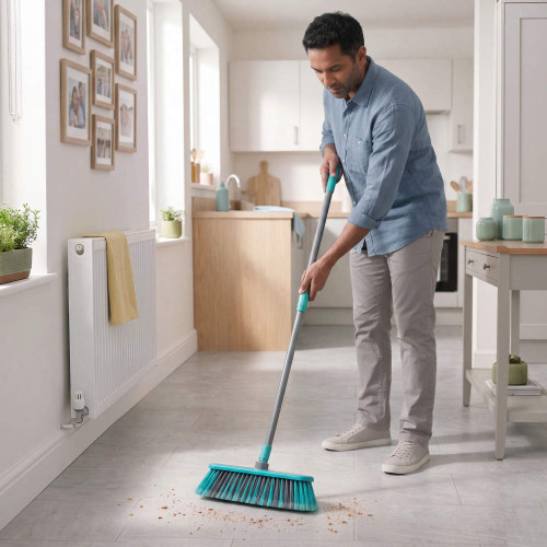 Man sweeping kitchen floor with teal broom