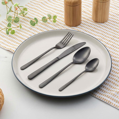 Set of matte black cutlery arranged on white plate