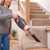 Handheld vacuum cleaner with crevice tool cleaning crumbs on carpeted stairs
