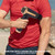 Black and gold massage gun used on upper arm, outdoors.