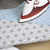 Ironing a pale blue shirt on a grey geometric patterned ironing board cover