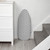 Grey ironing board with geometric pattern, stored upright beside stairs