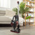 Cordless stick vacuum cleaner in a modern living room, shown upright on wooden floor