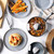 Set of grey non-stick pans and cookware with food, shown on a kitchen surface