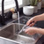 Hand drying a black slotted spoon over a kitchen sink
