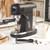 Black espresso coffee machine making coffee in a glass cup on kitchen counter