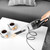 Handheld vacuum cleaner picking up crumbs from white table next to coffee cups