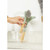 Green dish brush with bamboo handle in glass jar, shown held by hand