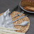 Set of four silver patterned cutlery pieces on placemat with bread in background