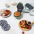 Green waffle maker with waffle plate, shown with waffles, mini pancakes, and doughnuts