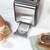Gunmetal toaster with removable crumb tray extended for cleaning, shown on kitchen worktop.