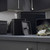 Set of black metal kitchen storage tins, one open showing tea bags inside.