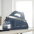 Navy blue Beldray Steam Surge Pro steam generator iron on ironing board in kitchen setting