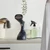 Handheld garment steamer in dark blue on laundry counter, basket and spray bottles nearby