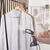 Handheld fabric steamer removing wrinkles from white shirt on hanger
