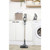 Cordless stick vacuum cleaner in gold and grey, upright in modern laundry room