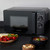 Black Salter microwave with control dials on kitchen counter, shown with soup and bread.
