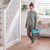 Woman carrying a grey folding step stool with turquoise handle