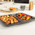 Oven tray with roast potatoes and mixed vegetables on kitchen worktop