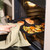 Oven tray with two seasoned chicken breasts and roast mixed vegetables being removed from oven