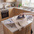 Compact ironing board with dog pattern and person ironing beige jumper in kitchen