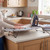 Tabletop ironing board with grey patterned cover and iron on kitchen counter