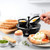 Black electric egg cooker with poached eggs, toast, and breakfast food on kitchen counter