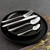 Four-piece stainless steel cutlery set with textured handles on black plate