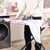 Person ironing white shirt on colourful ironing board in kitchen setting