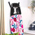 Person ironing white fabric on ironing board with pink and blue pomegranate print cover