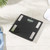 Black digital bathroom scale on tiled floor, shown from above