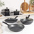 Black and white speckled non-stick cookware set including saucepans and frying pans on a kitchen counter.