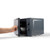 Black microwave oven with door open, hand placing a bowl inside