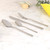Set of four stainless steel cutlery pieces on marble surface
