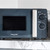 Black and silver Salter microwave with dial controls on marble countertop