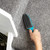 Hand using rubber pet hair remover brush on grey carpeted stairs